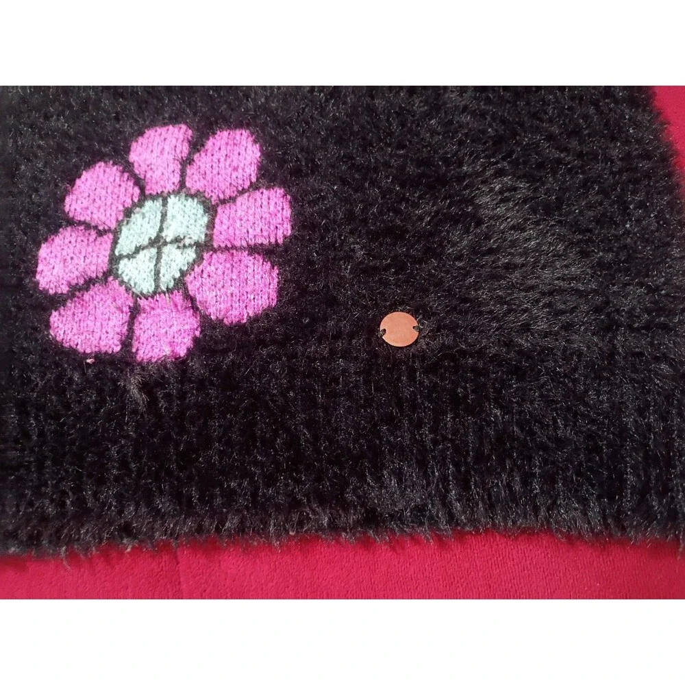 This is a Justice girls' black fuzzy eyelash sweater featuring pink and blue...